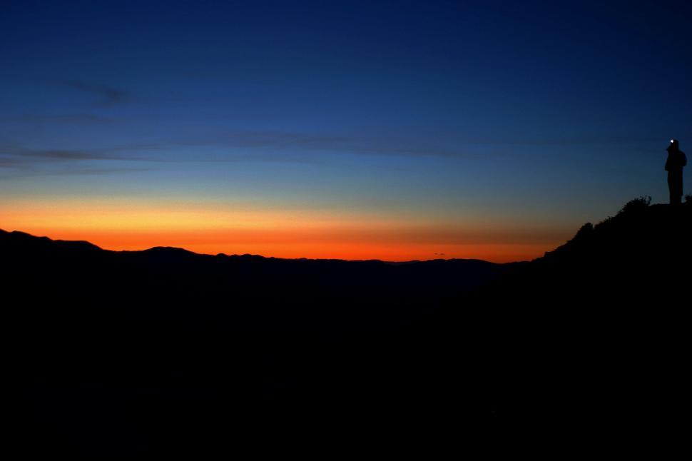 Free Image of Person Standing on Top of Hill at Sunset 