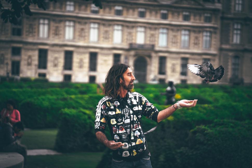 Free Image of Man Holding Bird in Front of Building 