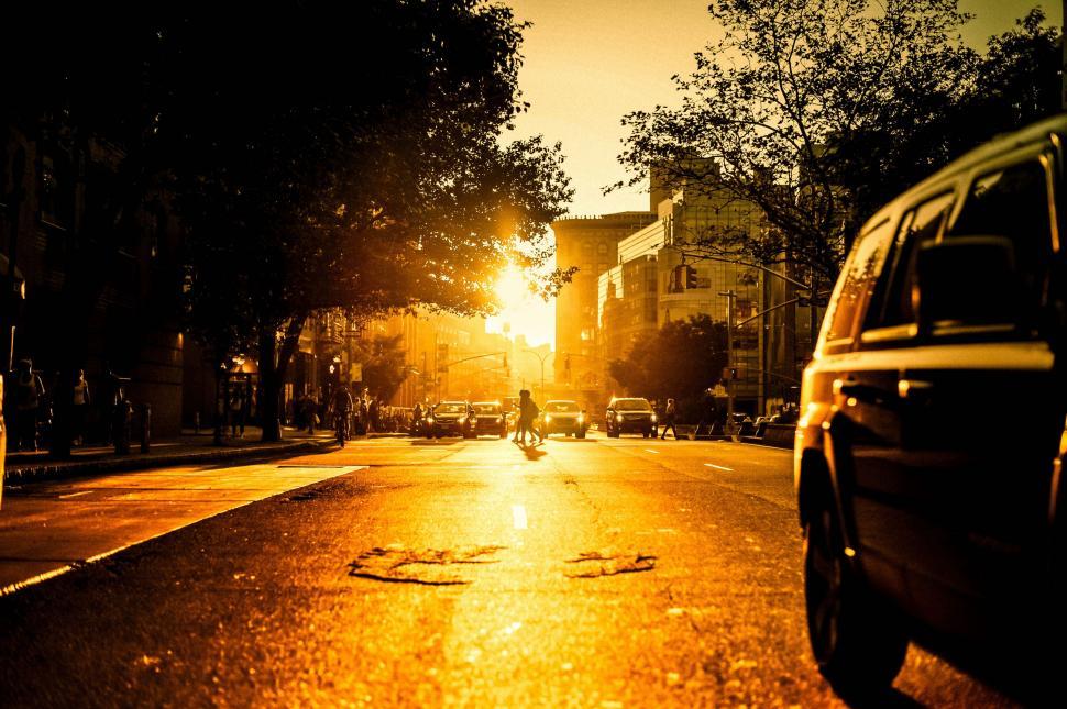 Free Image of Car Driving Down City Street Beside Tall Buildings 