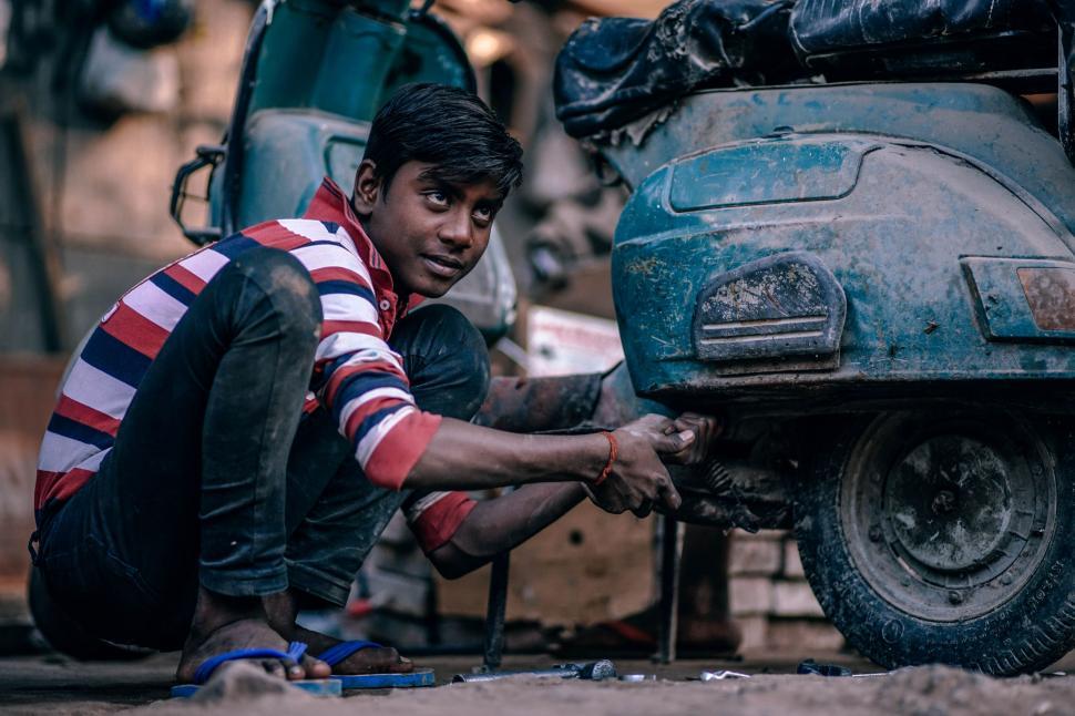 Free Image of Man Repairing Motorcycle on Street 