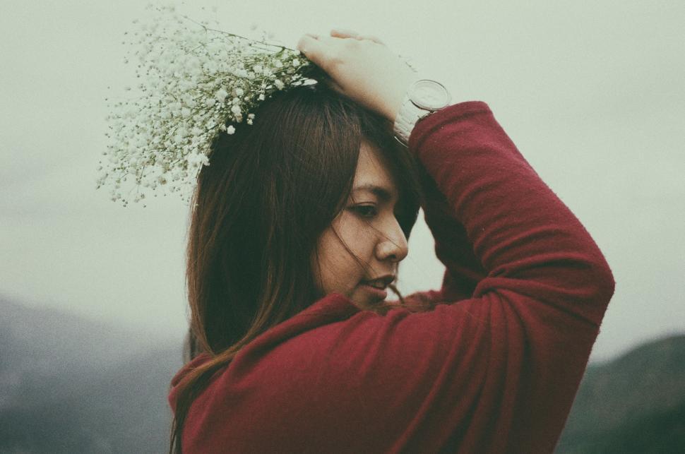 Free Image of Woman in Red Sweater Holding Hair in Wind 