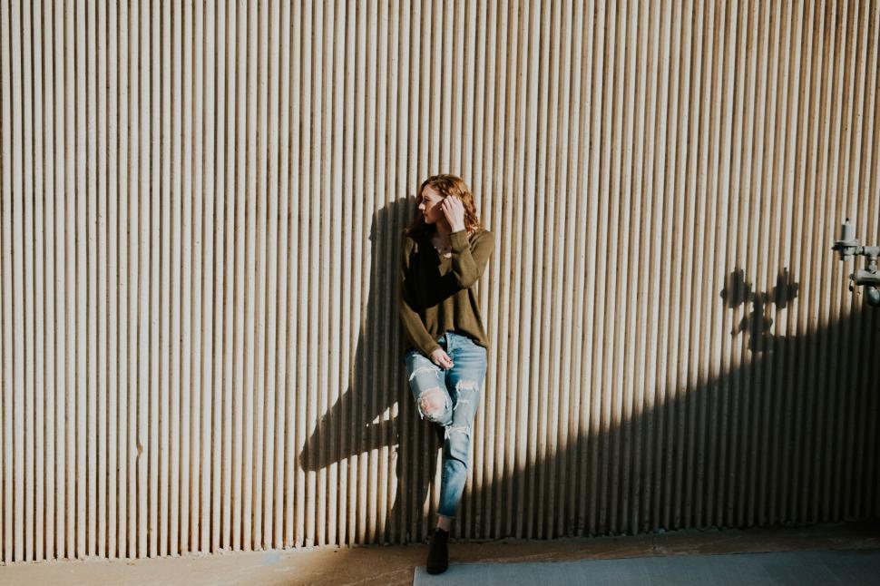Free Image of Man Leaning Against Wall Talking on Cell Phone 