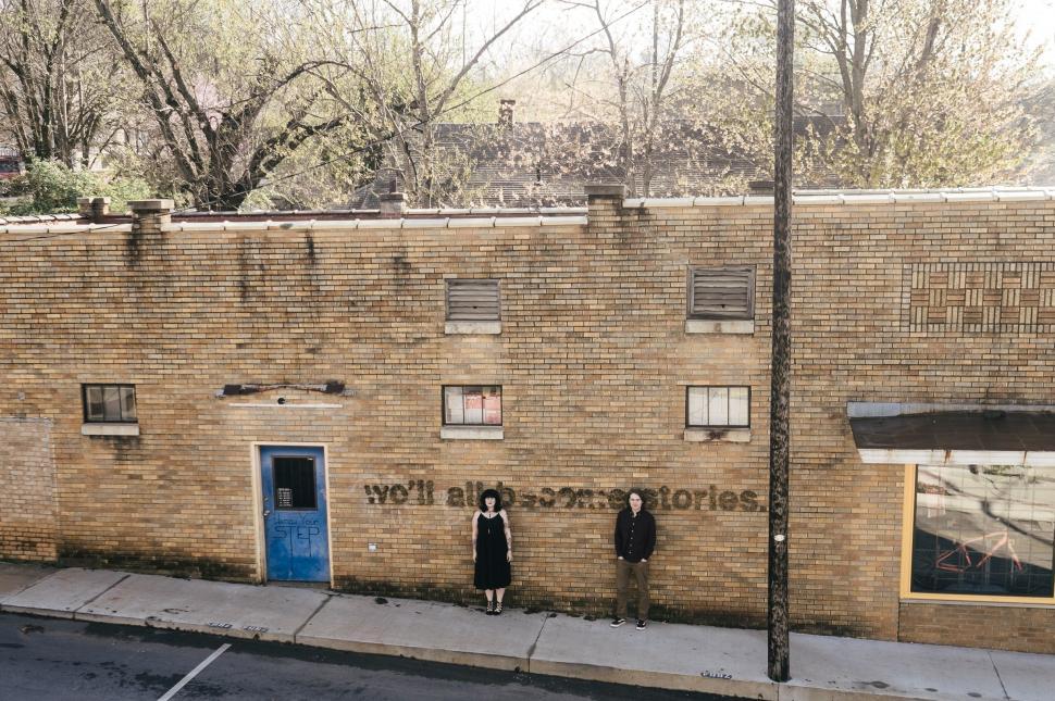 Free Image of Two People Standing in Front of a Brick Building 