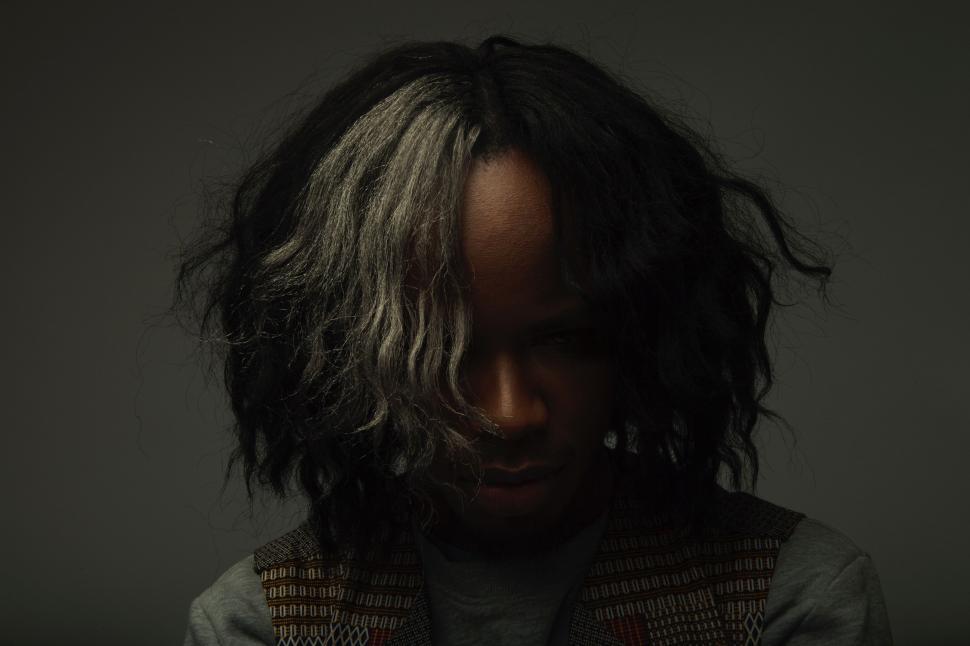 Free Image of Man With Long Hair Standing in Dark Room 