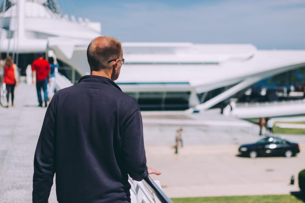 Free Image of Man Walking Down Sidewalk Carrying Suitcase 