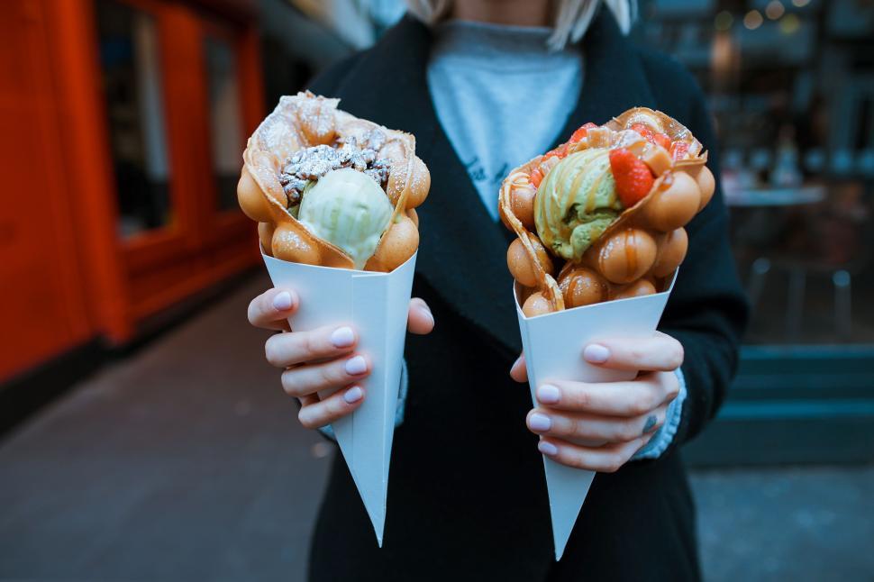 Free Image of Person Holding Two Cones of Food 