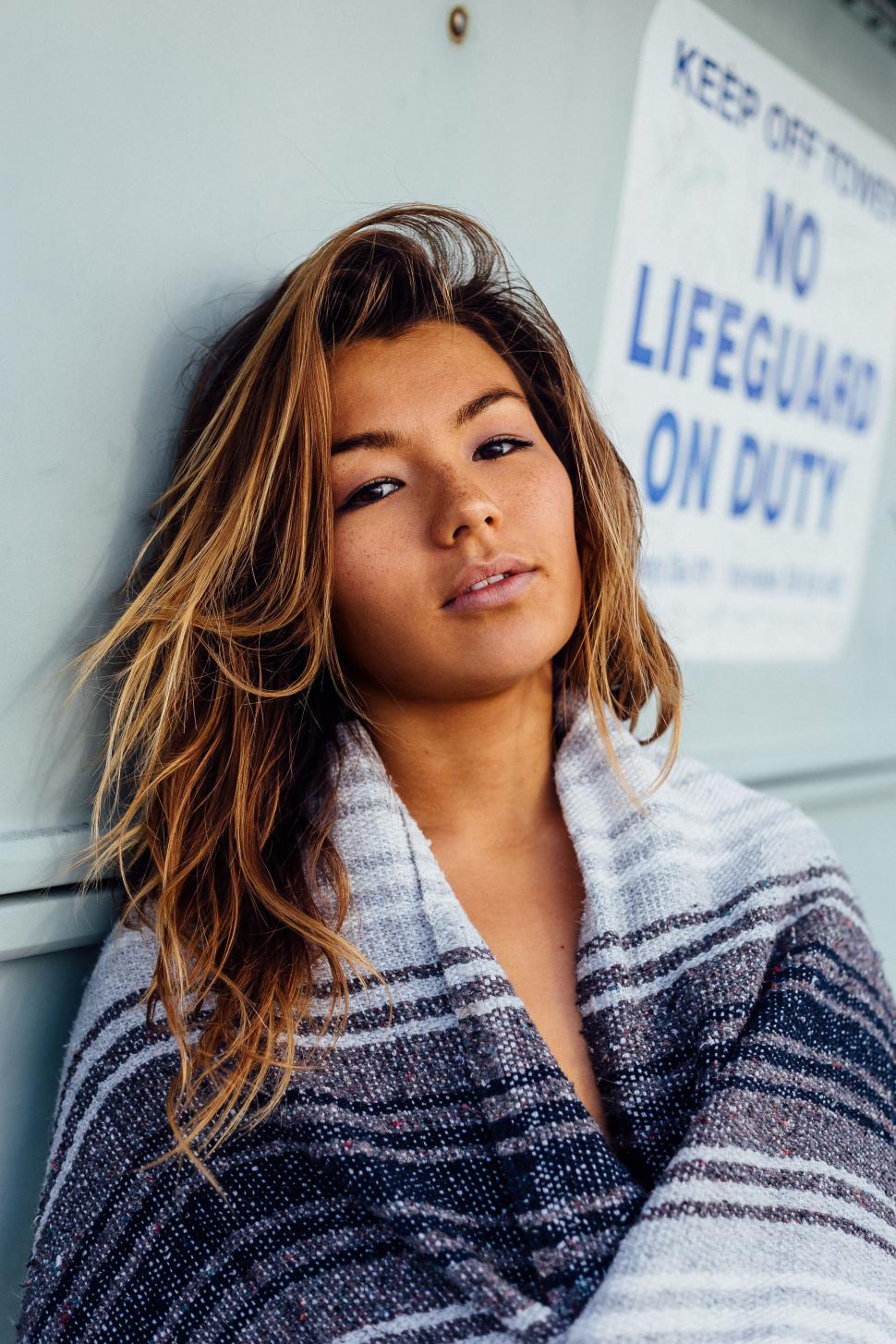 Free Image of Woman Leaning Against Wall With Crossed Arms 