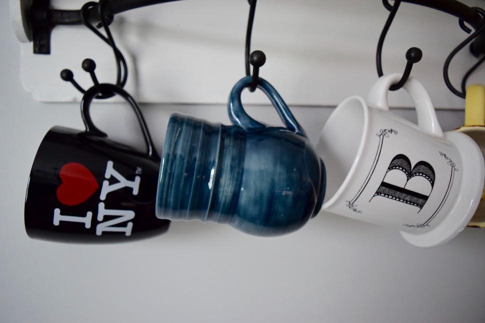 Free Image of Cups Hanging From Hooks on Wall 