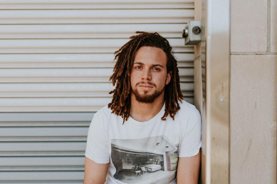 Free Image of Man With Dreadlocks Sitting in Front of Garage Door 