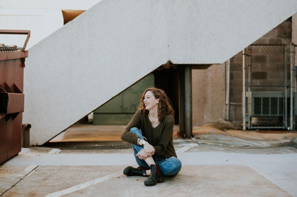 Free Image of Woman Sitting on Ground in Front of Staircase 