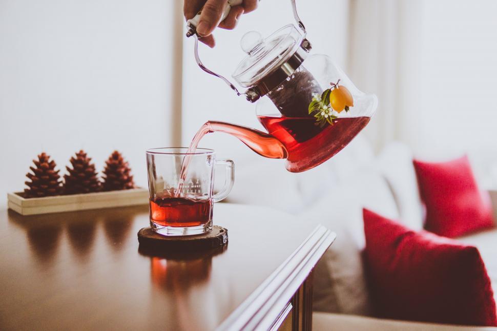 Free Image of Person Pouring Tea Into Glass on Table 