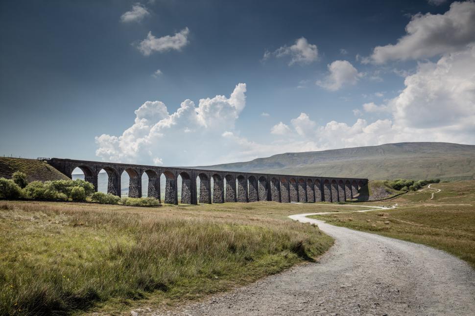 Free Image of Train Crossing Bridge Over Green Field 