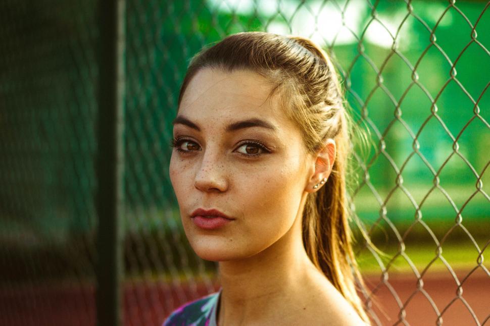 Free Image of Woman Standing in Front of Chain Link Fence 