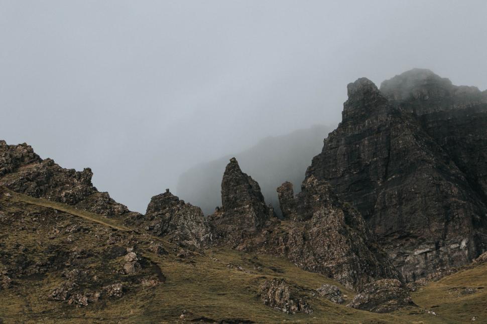 Free Image of A Flock of Birds Flying Over a Rocky Mountain 