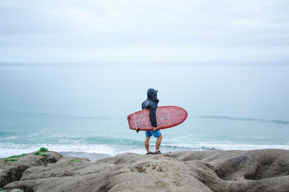 Free Image of Man Holding Surfboard on Sandy Beach 