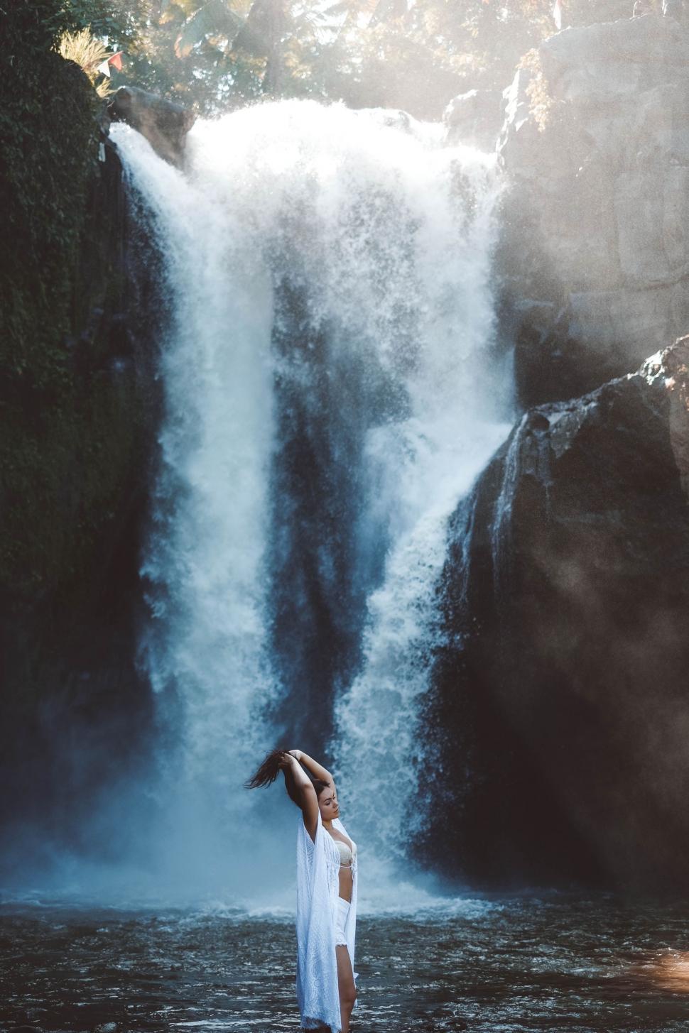 Free Image of Woman Standing in Front of Waterfall 