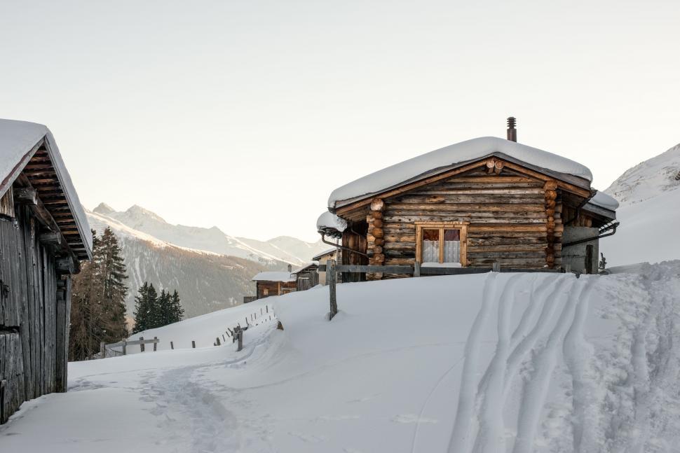 Free Image of Log Cabin on Snowy Mountain With Background Mountains 
