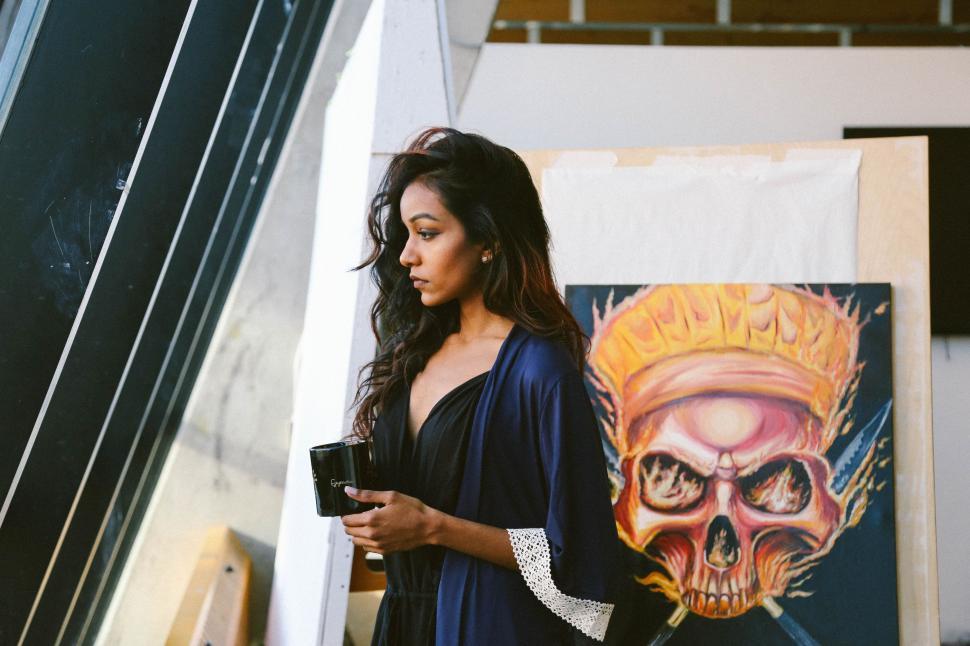 Free Image of Woman Standing Next to Painting Holding a Camera 