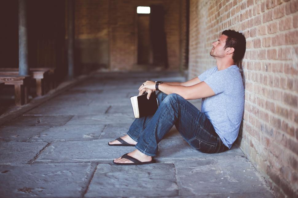 Free Image of Man Sitting Next to Brick Wall 