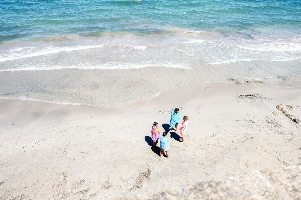 Free Image of Three People Walking on a Beach Near the Ocean 