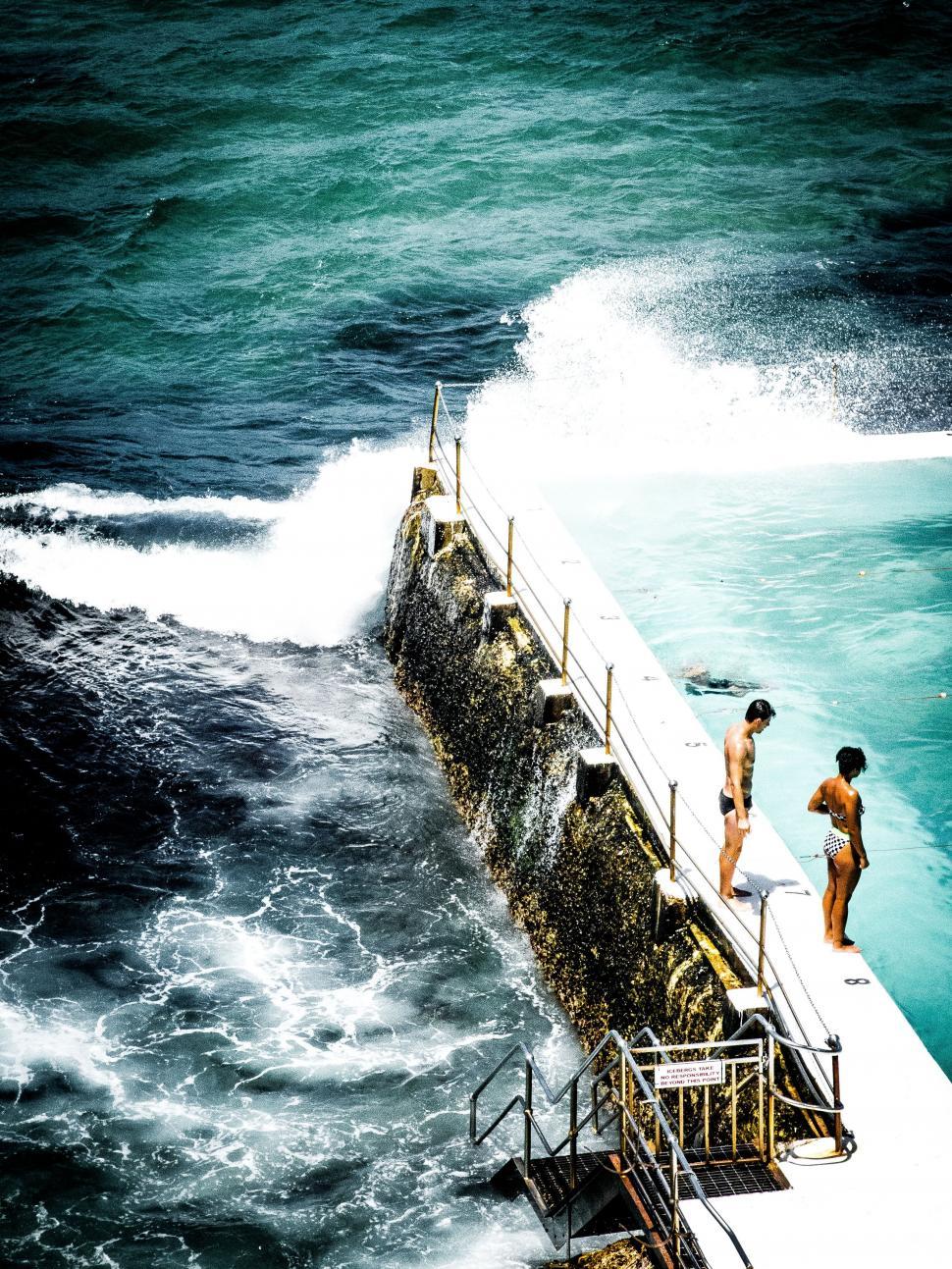 Free Image of Couple Standing on Pier by Ocean 
