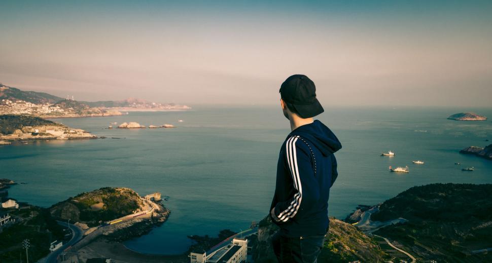 Free Image of Man Standing on Cliff Overlooking Water 