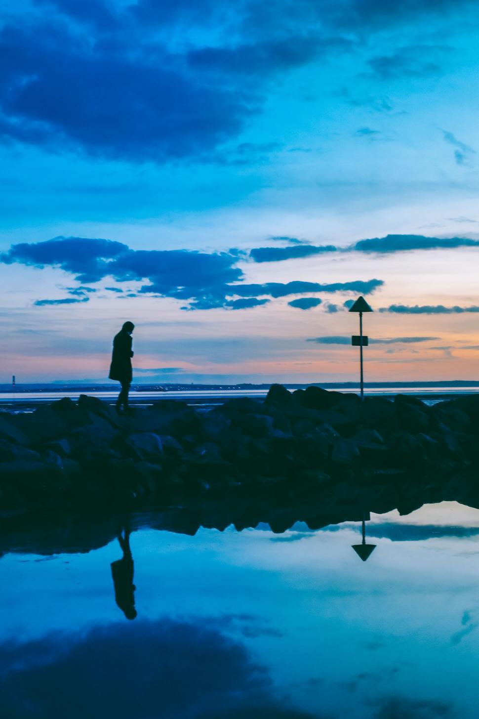 Free Image of Person Standing on Beach Next to Body of Water 
