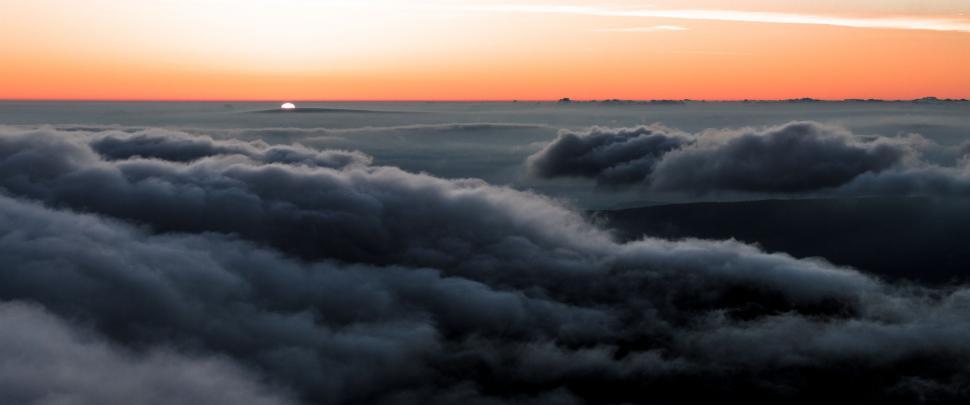 Free Image of Sun Setting Over Clouds in Sky 