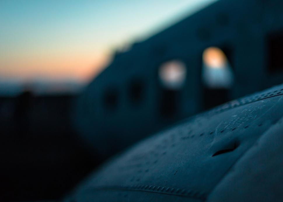 Free Image of Blurry Plane Flying Past Building 