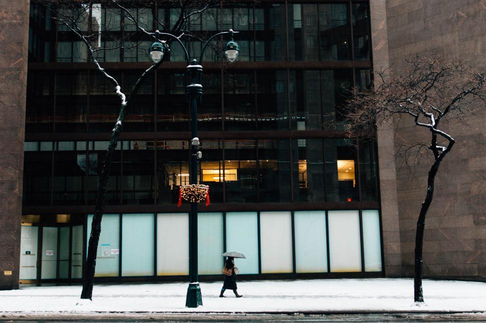 Free Image of Person Walking Down Street in Front of Tall Building 