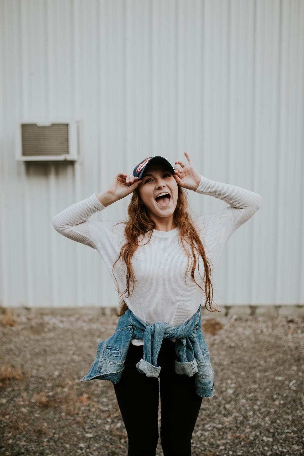 Free Image of Woman Standing In Front of Building With Hands on Head 