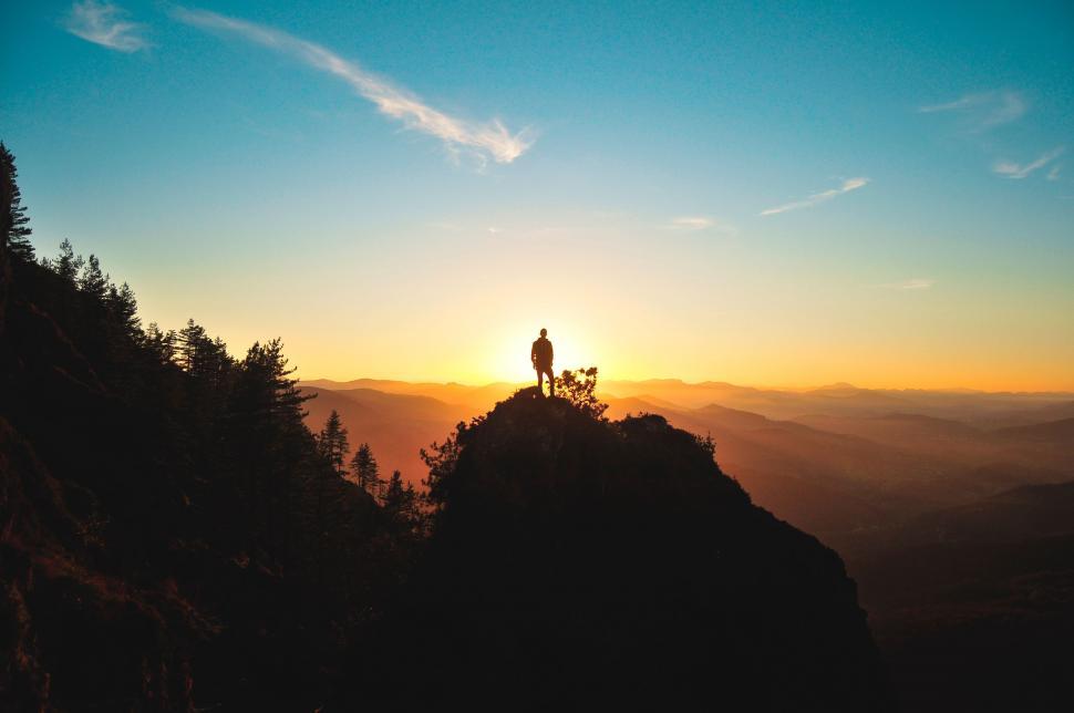 Free Image of Person Standing on Top of a Mountain at Sunset 