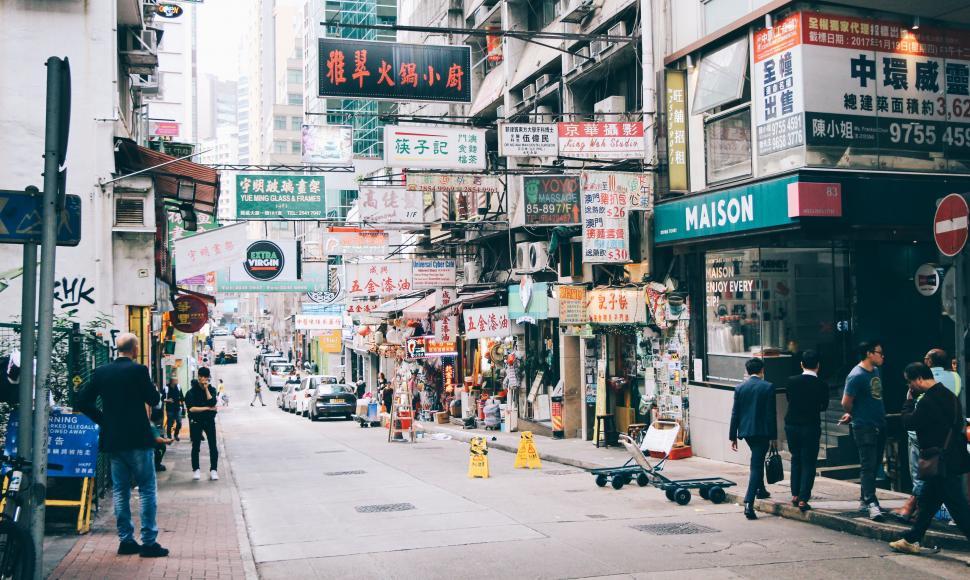Free Image of Group of People Walking Down Street Next to Tall Buildings 