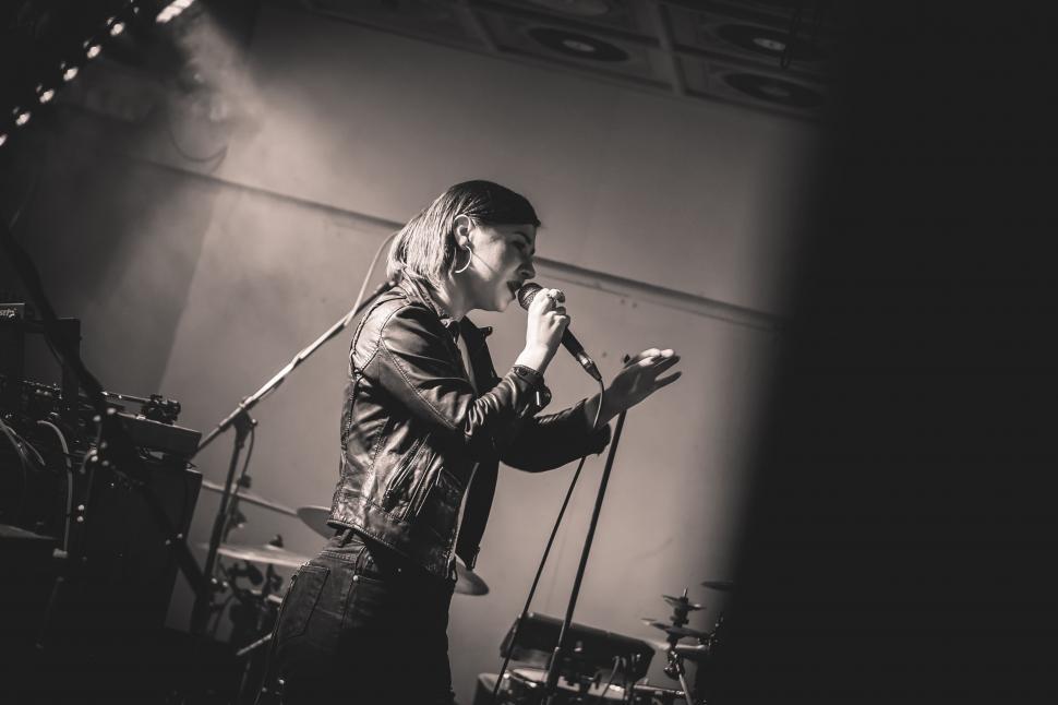 Free Image of Man Standing on Stage Holding Microphone 