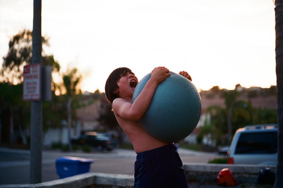 Free Image of Man Holding Large Blue Ball 