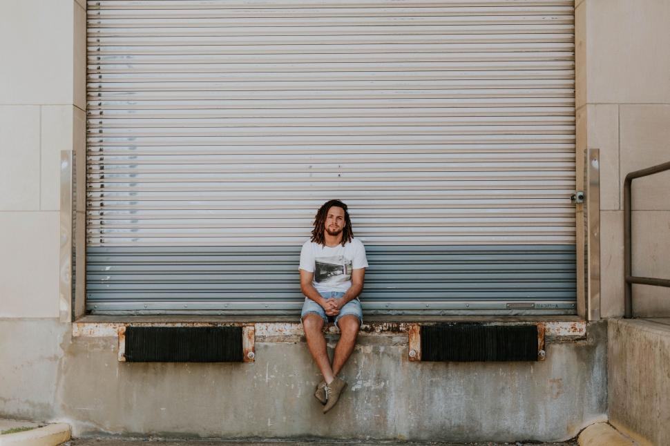Free Image of Woman Sitting on Bench in Front of Garage Door 