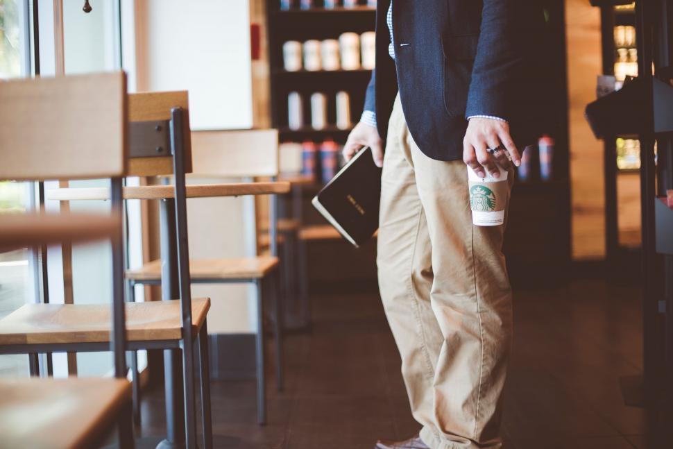 Free Image of Man Holding Book and Drink in Library 