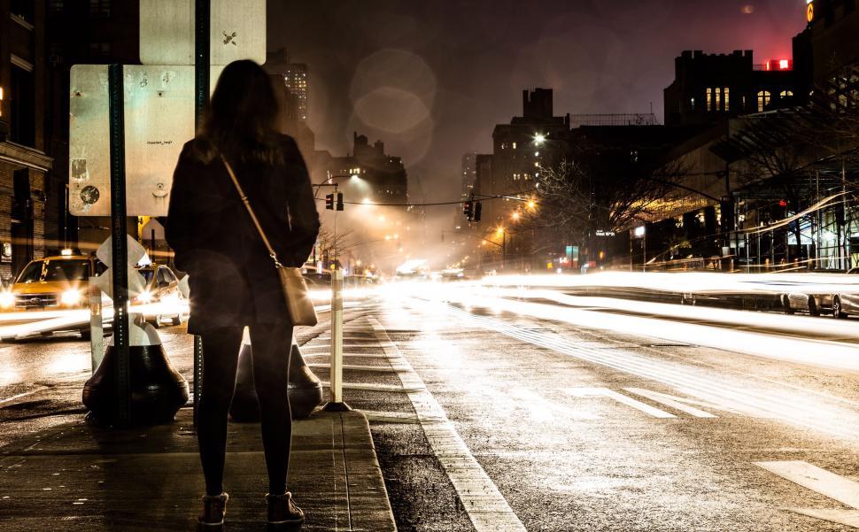 Free Image of Woman Standing on Side of Street at Night 