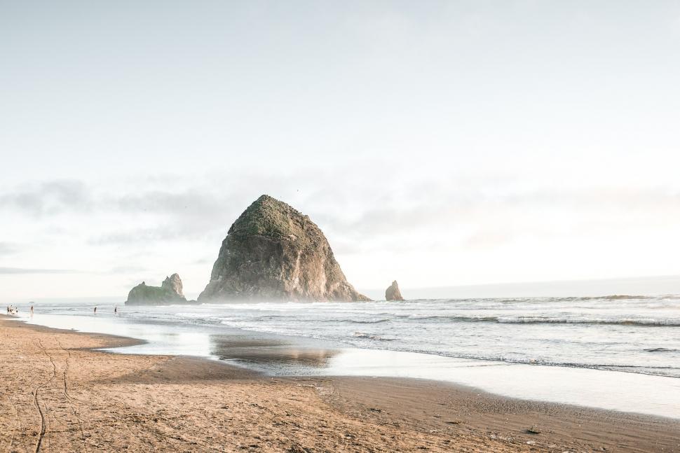 Free Image of Sandy Beach With Rock Formation in Background 