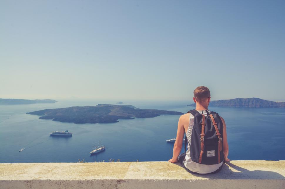 Free Image of Man Sitting on Ledge Overlooking Water 