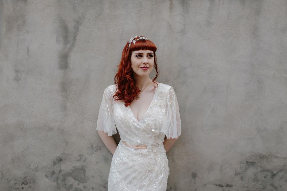 Free Image of Woman in White Dress Standing in Front of Wall 