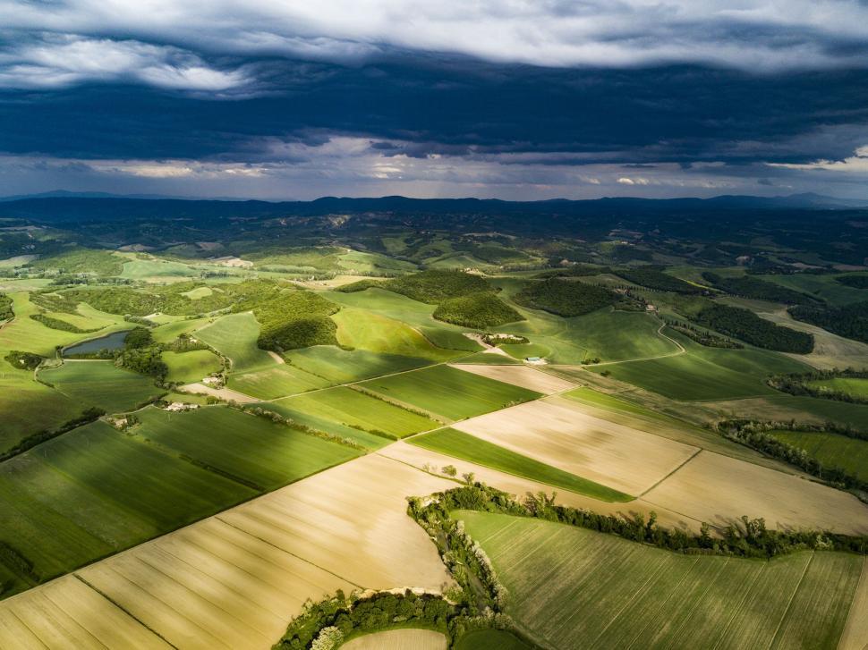 Free Image of Aerial View of Green Field Under Cloudy Sky 