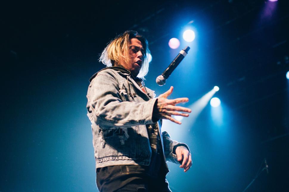 Free Image of Man Standing on Stage Holding Microphone 