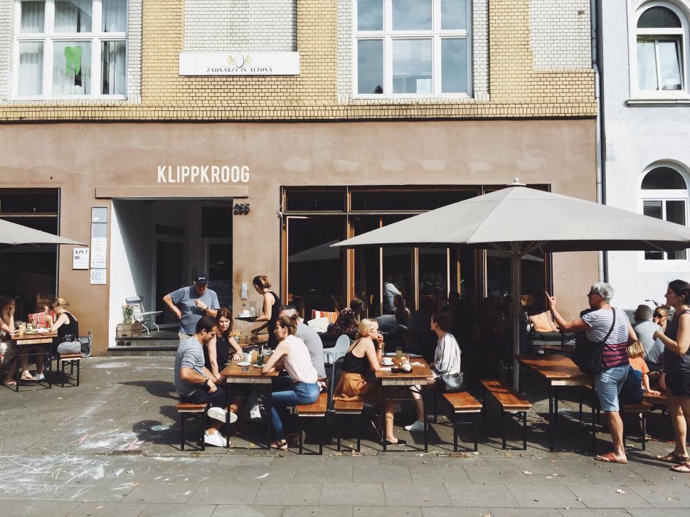 Free Image of Group of People Sitting at Tables Outside of a Building 