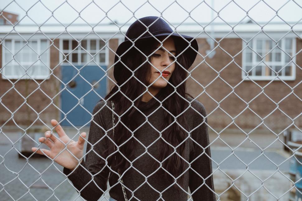 Free Image of Man Standing Behind Chain Link Fence 