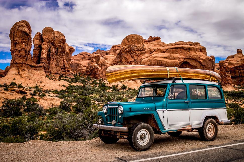 Free Image of Blue Jeep With Surfboard on Top 