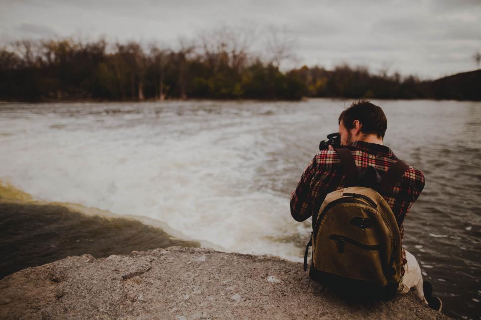Free Image of Person Sitting on Rock by Water 