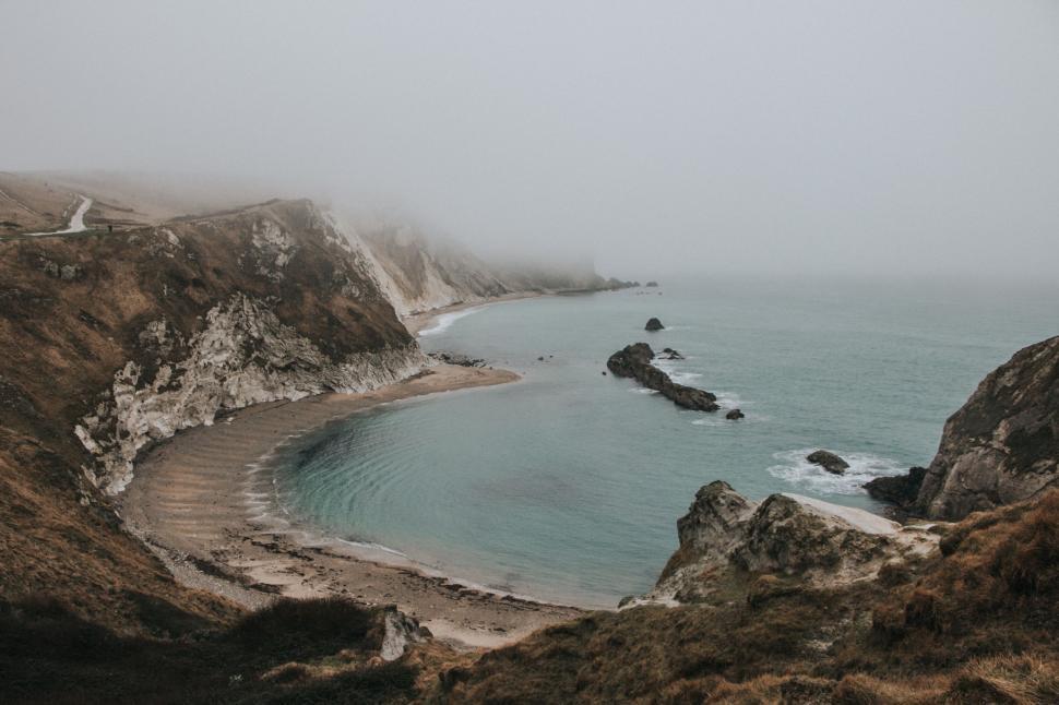 Free Image of Majestic Mountains Surrounding Foggy Body of Water 