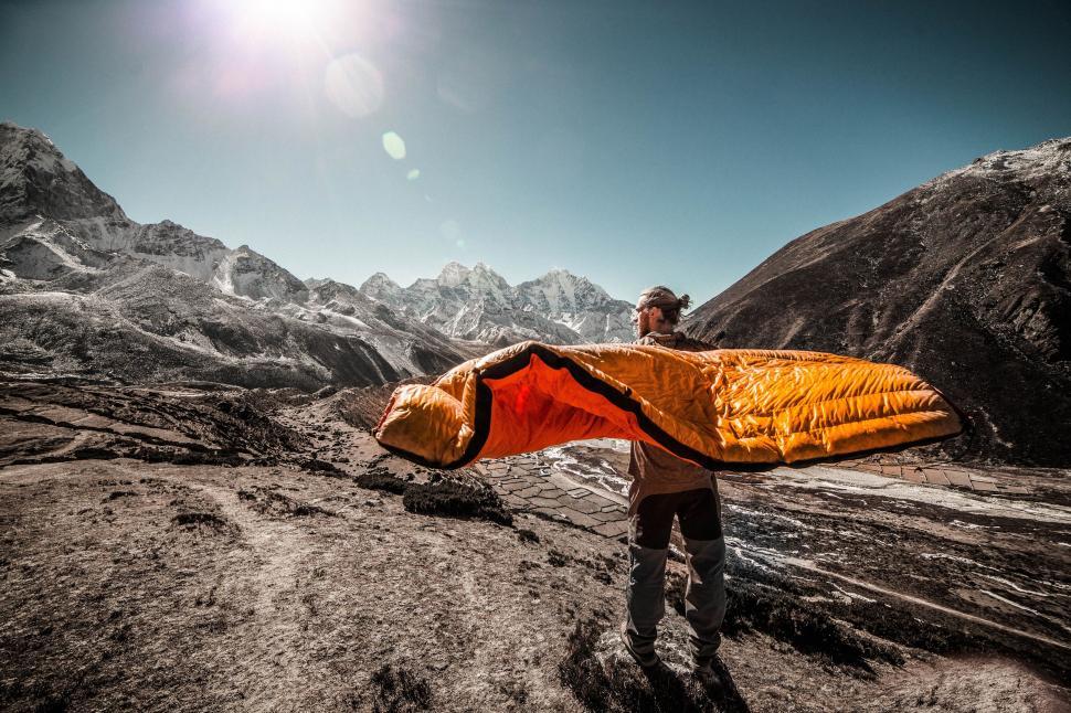 Free Image of Man Standing on Mountain Holding Yellow and Black Kite 