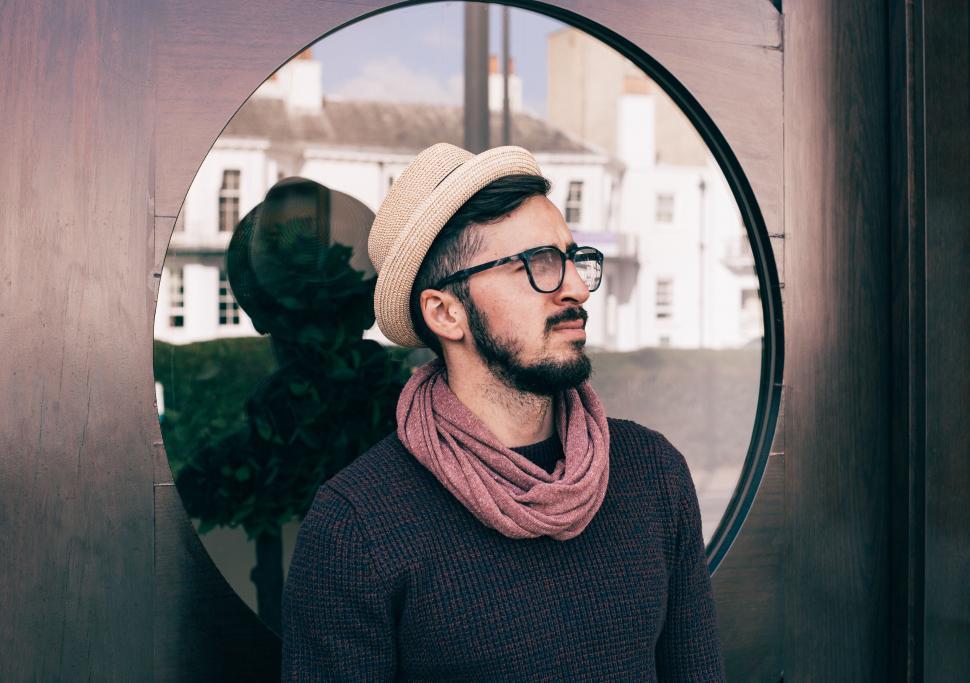 Free Image of Man in Hat and Scarf Standing by Round Mirror 